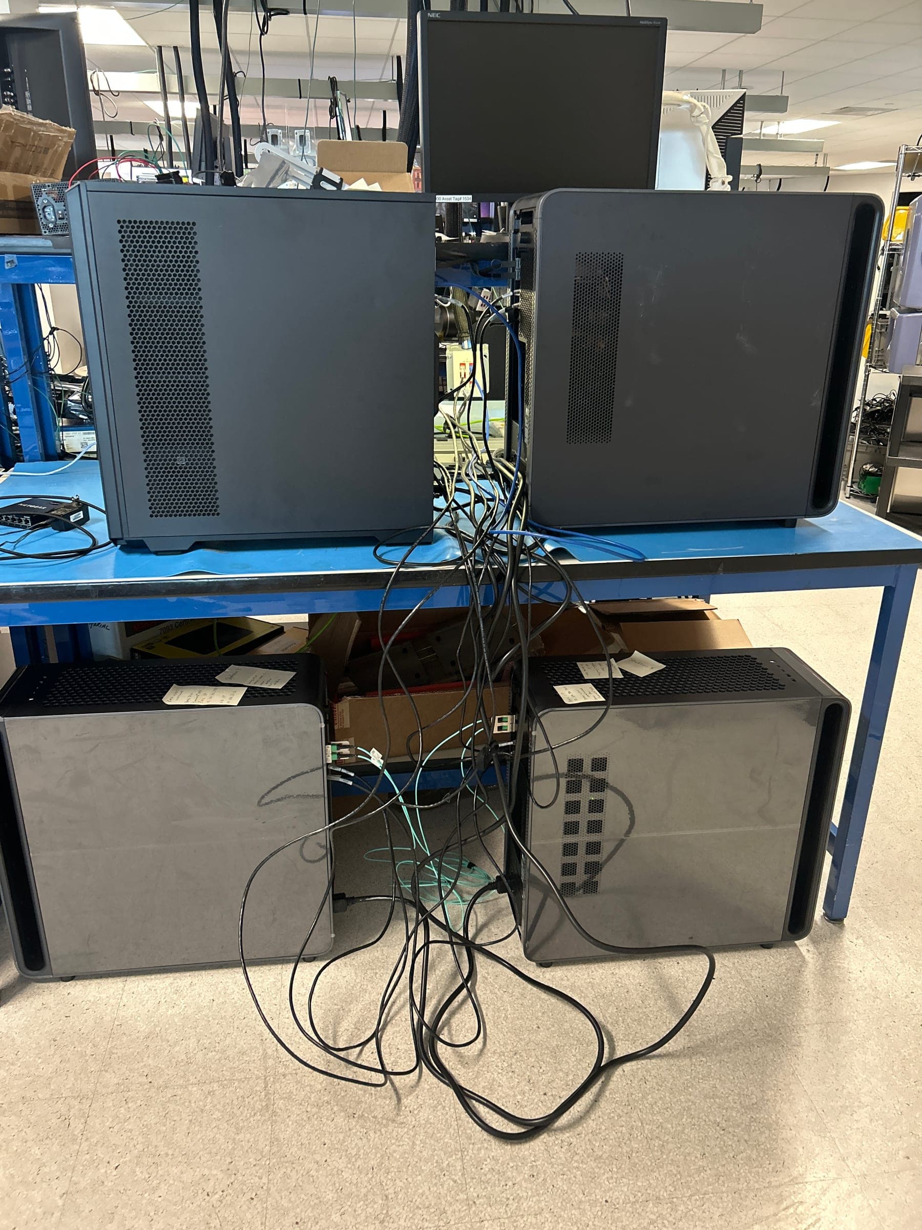 Four workstation towers on a lab bench, joined by a tangle of network cables