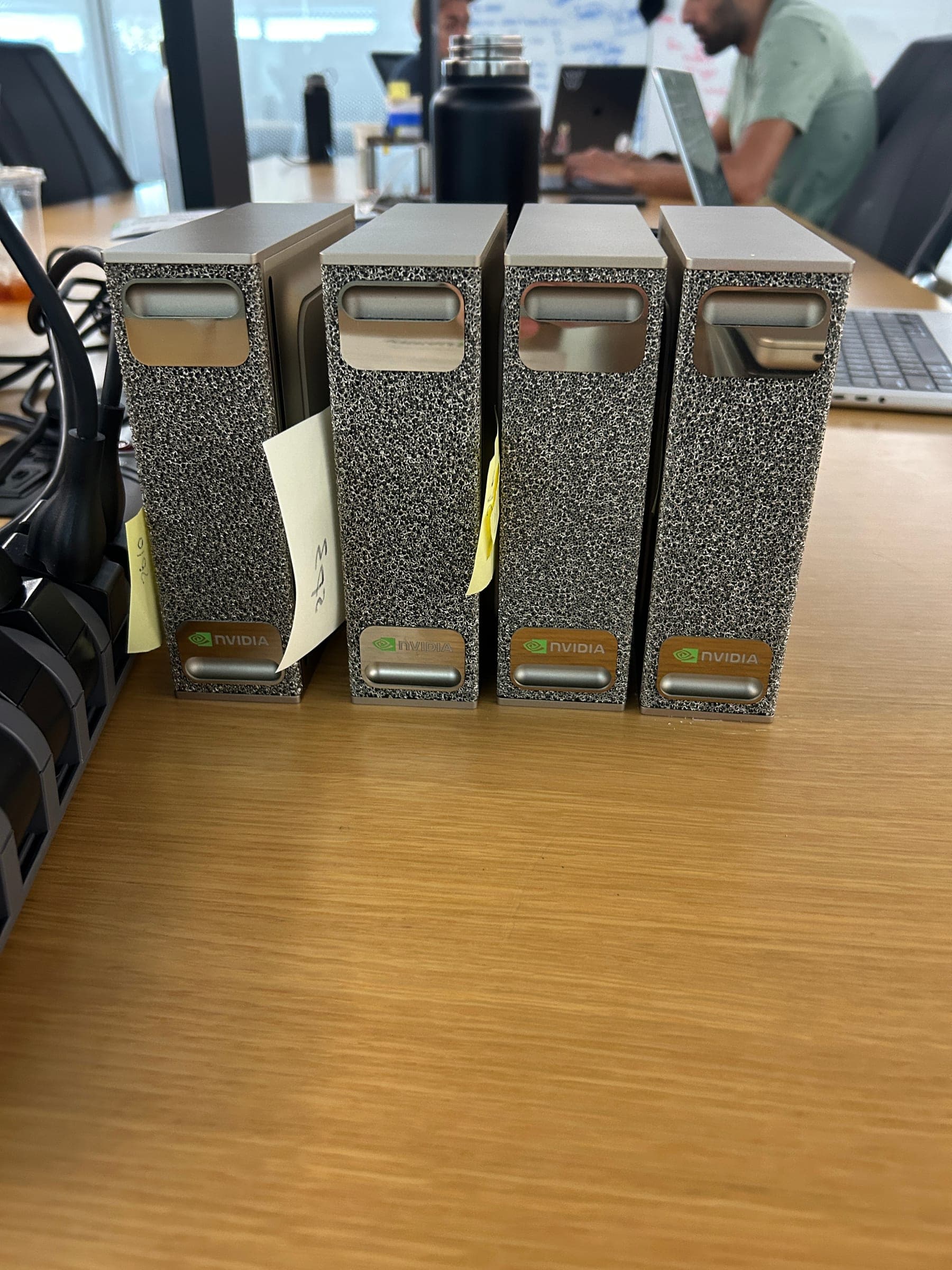 Four gold DGX Spark units standing side by side on an office desk